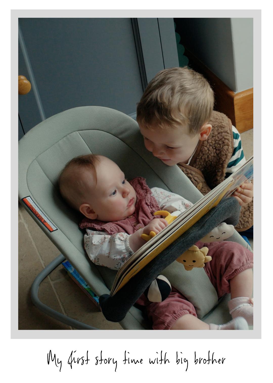 A young child reads a book to a baby in a bouncer, with a plush toy and soft lighting creating a warm, cozy atmosphere.